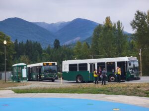 Two buses in a rural area with misty mountains in the background