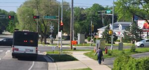 A bus in a suburban area with someone walking along a sidewalk